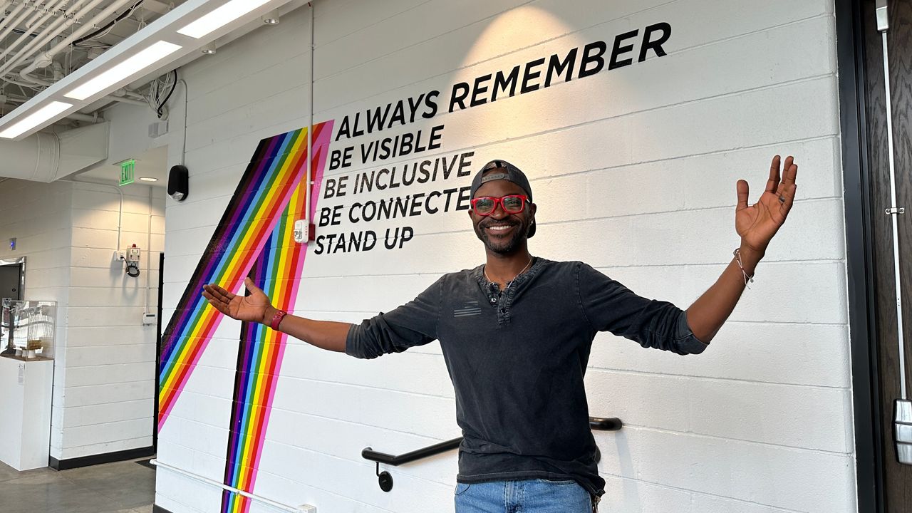 Densil Porteous, the executive director of Stonewall Columbus stands in front of a mural inside the office.