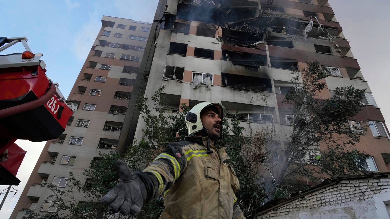A firefighter calls out his colleagues at the scene of an explosion in a residence compound in northern Tehran, Iran, Friday, June 13, 2025. (AP Photo/Vahid Salemi)