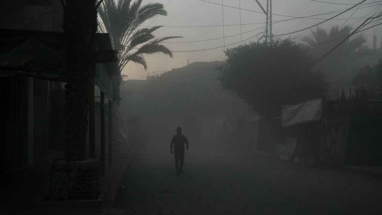 A Palestinian walks on a smoke-filled street after an Israeli airstrike in Deir al Balah, Gaza Strip, Tuesday, Aug. 6, 2024. (AP Photo/Abdel Kareem Hana)