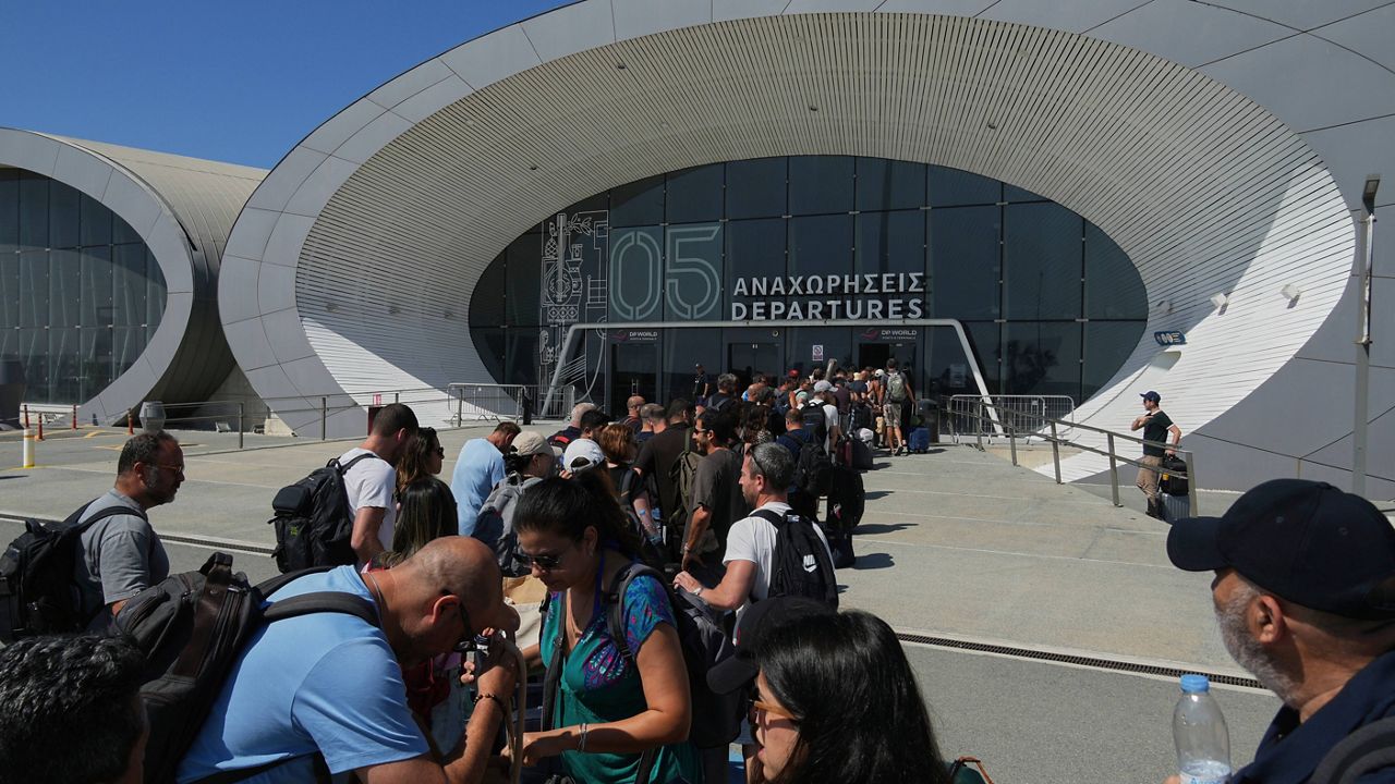Israelis line up at the entrance to the departures terminal at Cyprus' main port in Limassol where they'll board the Israeli cruise ship Crown Iris to take them back to their homeland, on Thursday, June 19, 2025. (AP Photo/Petros Karadjias)