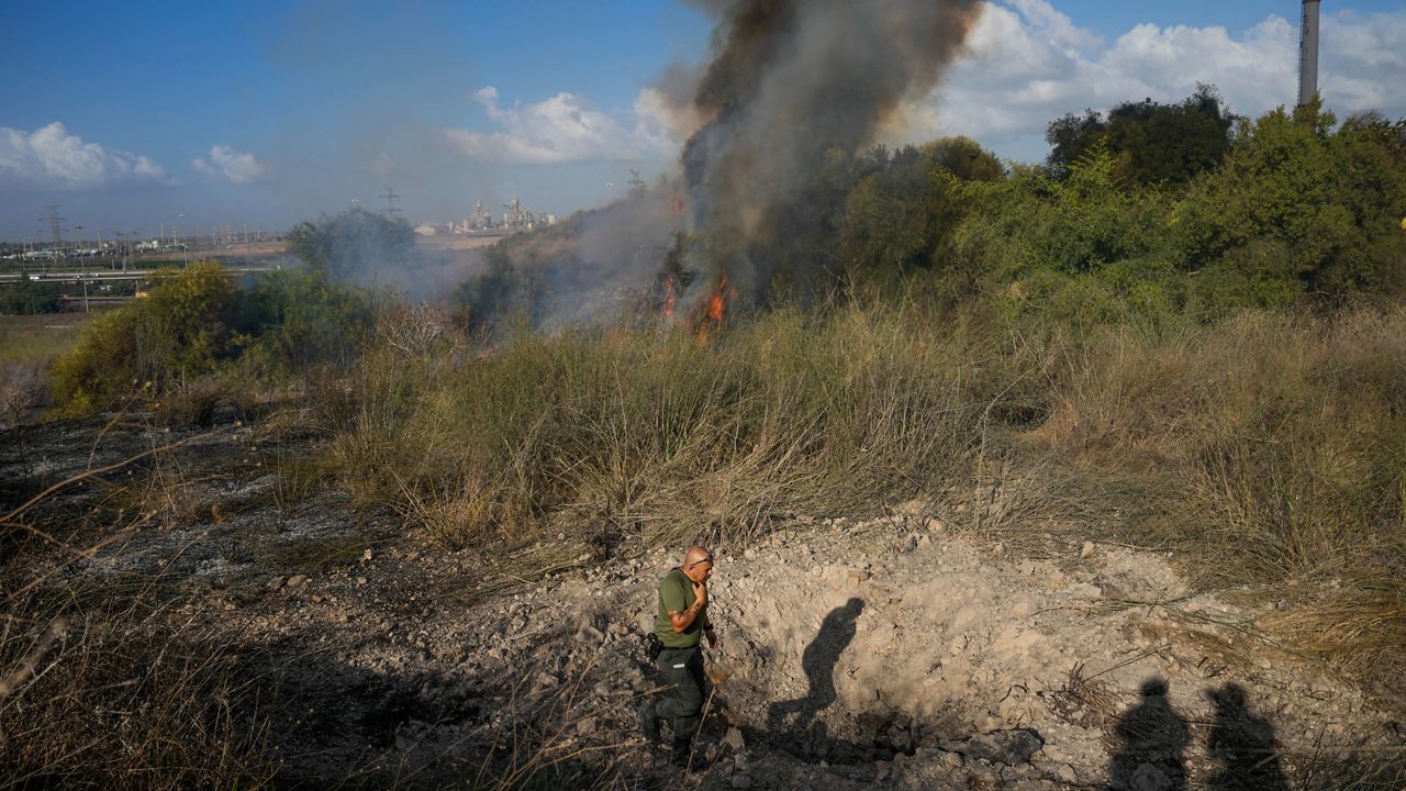 A police officer inspects the area around a fire after the military said it fired interceptors at a missile launched from Yemen that landed in central Israel on Sunday, Sept. 15, 2024. (AP Photo/Ohad Zwigenberg)