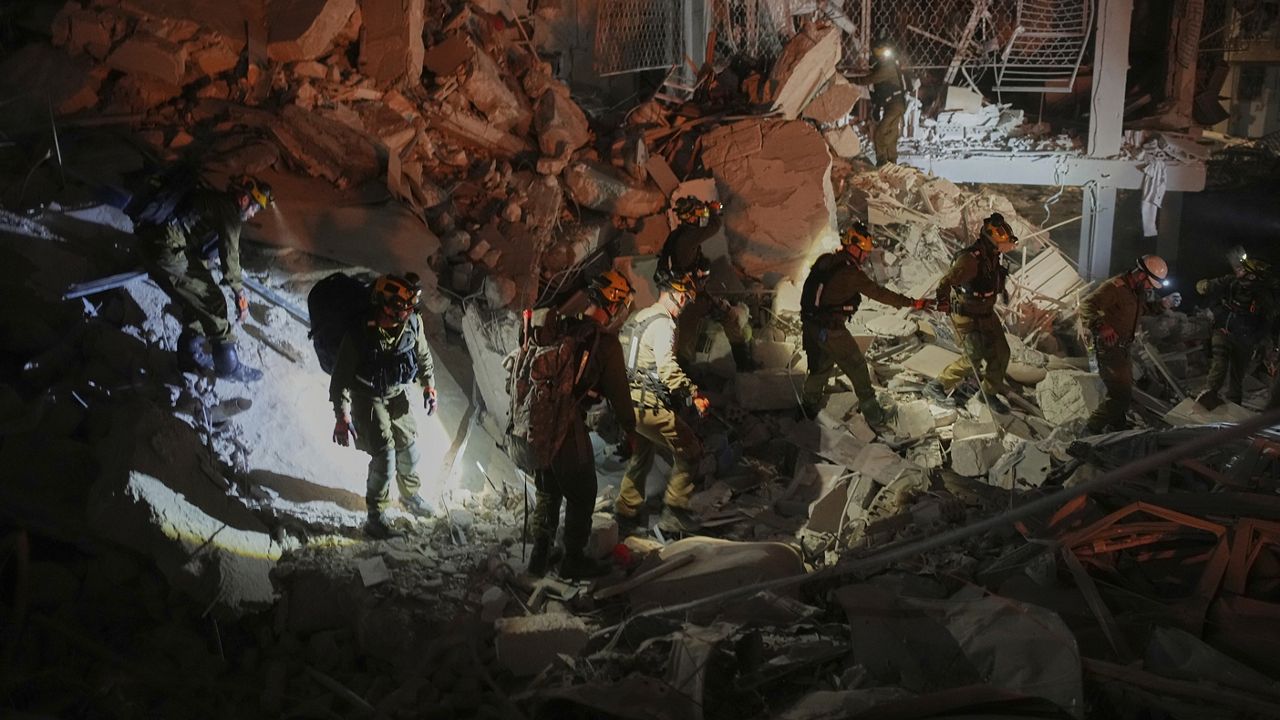 Israeli security forces inspect a destroyed building that was hit by a missile fired from Iran, near Tel Aviv, Israel, early Sunday, June 15, 2025. (AP Photo/Ohad Zwigenberg)