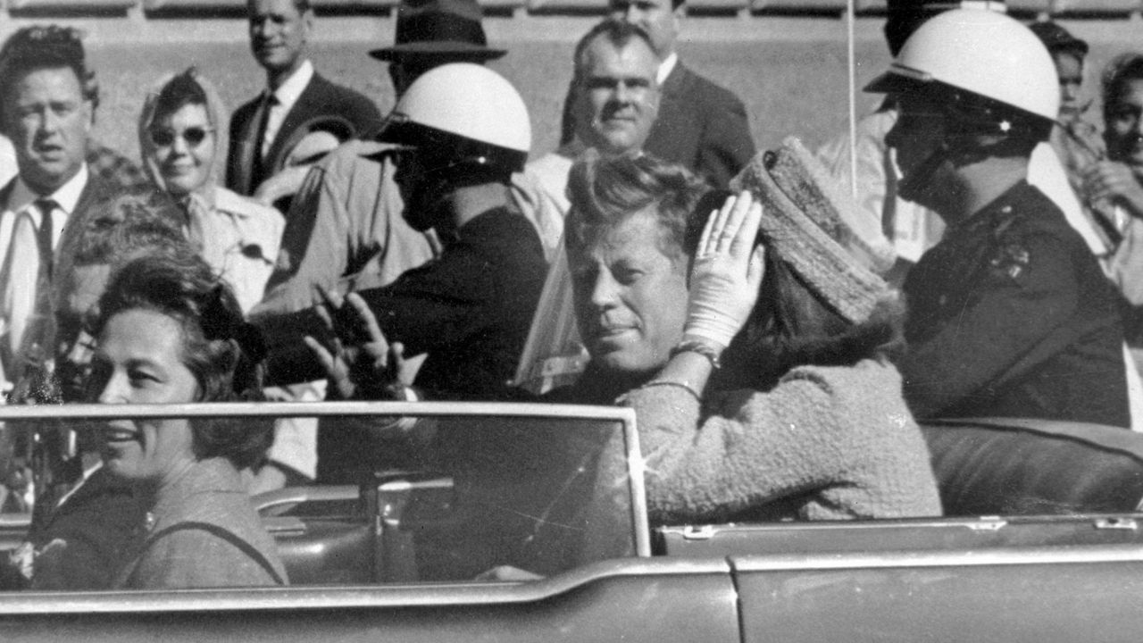 President John F. Kennedy waves from his car in a motorcade approximately one minute before he was shot, Nov. 22, 1963, in Dallas. (AP Photo/Jim Altgens, File)