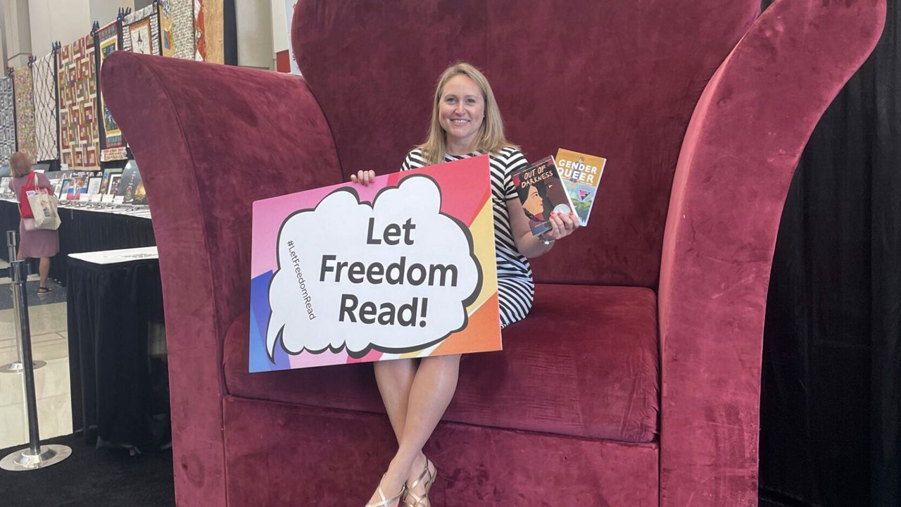 School librarian Jamie Gregory, from South Carolina, displays two books that have been repeatedly challenged in the United States, while seated at the Banned Books from the Big Chair station at the American Library Association's annual conference in Chicago, June 24, 2023. The two books are: "Gender Queer," by Maia Kobabe, and "Out of Darkness," by Ashley Hope Pérez. (AP Photo/Claire Savage)