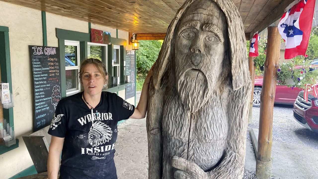 Pauline Bauer leans against a wooden statue outside Bob's Trading Post, her restaurant in Hamilton, Pa., July 21, 2021. (AP Photo/Michael Kunzelman)