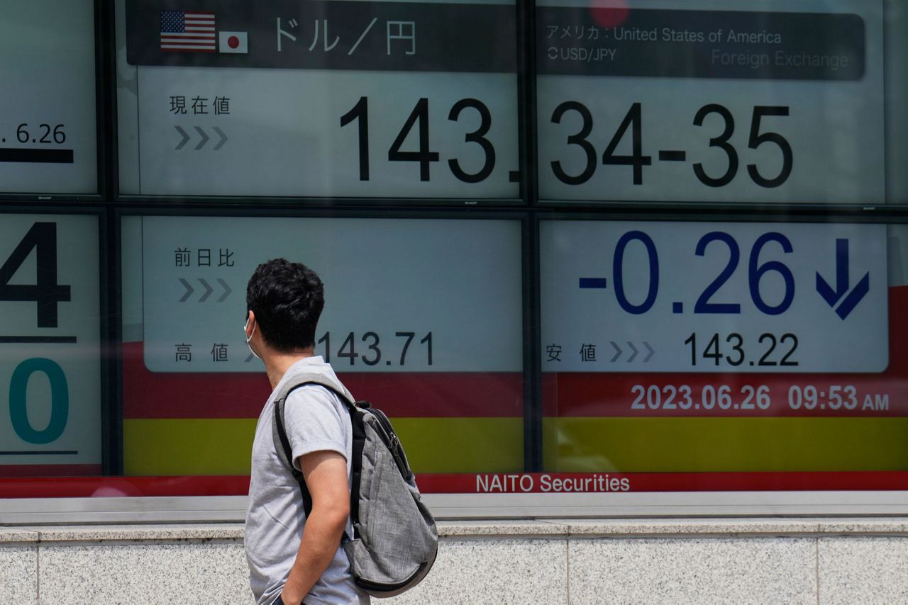 A man looks at monitors showing Japanese yen's foreign exchange rate a...