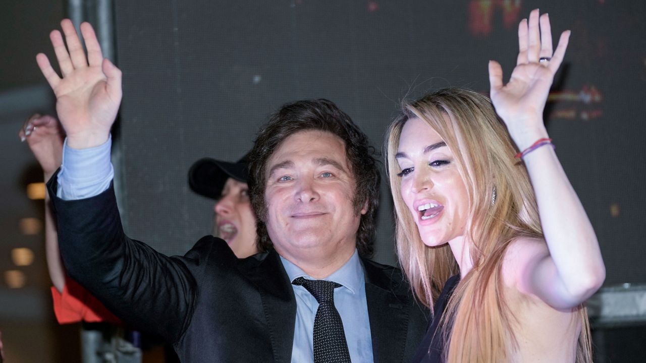 Presidential candidate of the Liberty Advances coalition Javier Milei, right, and his girlfriend Fatima Florez wave to supporters outside his campaign headquarters after winning the runoff election in Buenos Aires, Argentina, Sunday, Nov. 19, 2023. (AP Photo/Rodrigo Abd)