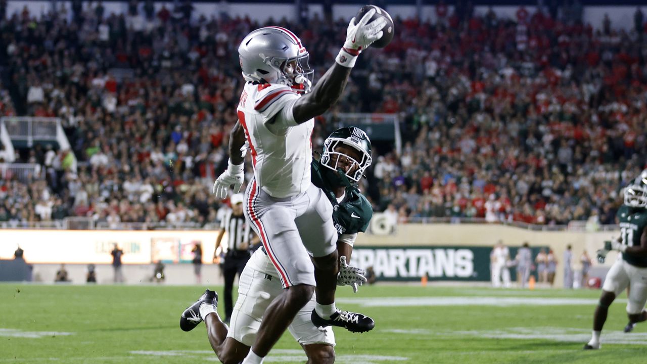 Ohio State wide receiver Jeremiah Smith, left, makes a one-handed catch for a touchdown against Michigan State defensive back Ed Woods during the first half of an NCAA college football game, Saturday, Sept. 28, 2024, in East Lansing, Mich. (AP Photo/Al Goldis)