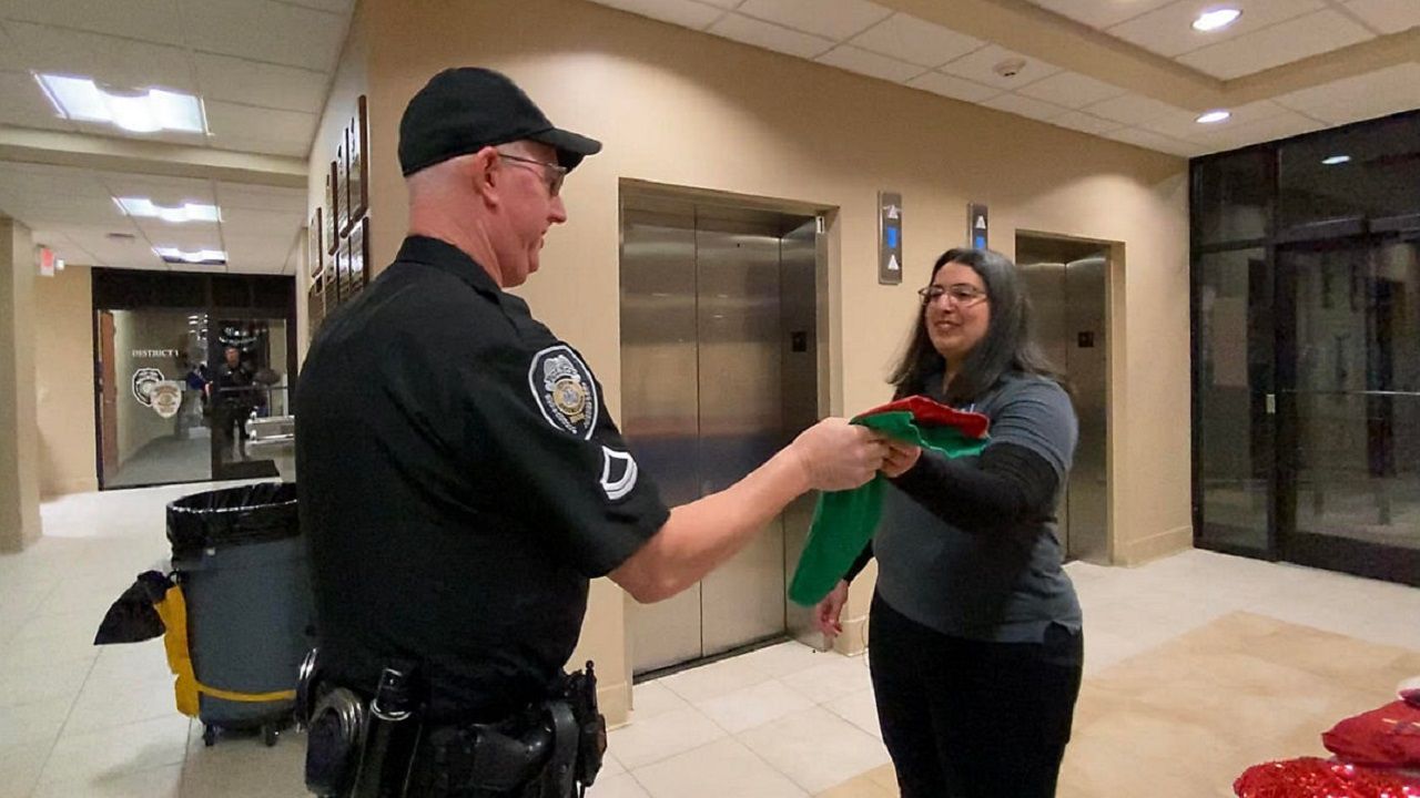 Corie Hampton giving stuffed stocking to GPD Officer (Spectrum News 1/Zyneria Byrd)
