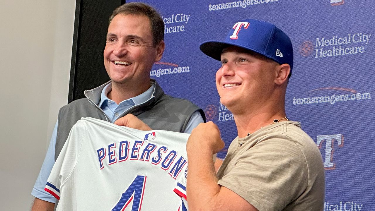 Texas Rangers president of baseball operations Chris Young, left, poses for photos with Joc Pederson during a news conference announcing Pederson's two-year contract with the team, Monday, Dec. 30, 2024, in Arlington, Texas. (AP Photo/Stephen Hawkins)