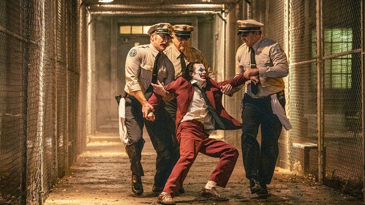 This image released by Warner Bros. Pictures shows Joaquin Phoenix, foreground center, and Brendan Gleeson, background center, in a scene from "Joker: Folie à Deux." (Niko Tavernise/Warner Bros. Pictures via AP)