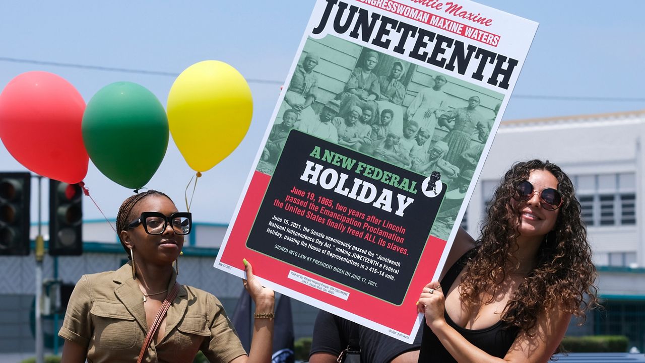 People hold a sign in their car during a car parade to mark Juneteenth on June 19, 2021, in Inglewood, Calif.  (AP Photo/Ringo H.W. Chiu, File)