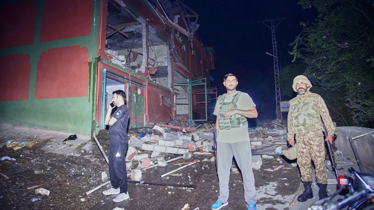 Security force officials stand outside a damaged building at a site of a suspected Indian missile attack near Muzaffarabad, the capital of Pakistan controlled Kashmir, in Wednesday, May 7, 2025. (AP Photo/M.D. Mughal)