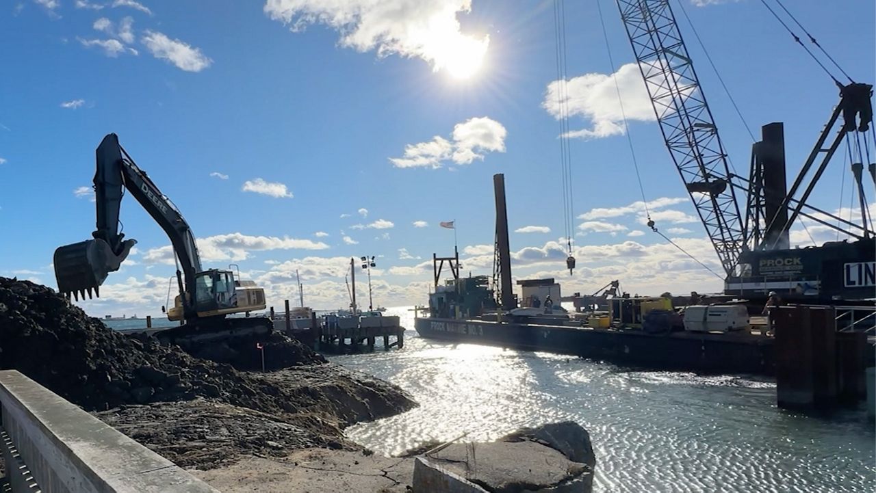 A crane prepares to hoist parts from a barge, right, while heavy equipment digs at the commercial fishing pier at Cape Porpoise in Kennebunkport Friday. The town is in the middle of an $8 million project to raise the pier two feet, protecting it from storm surges. (Spectrum News/Sean Murphy)