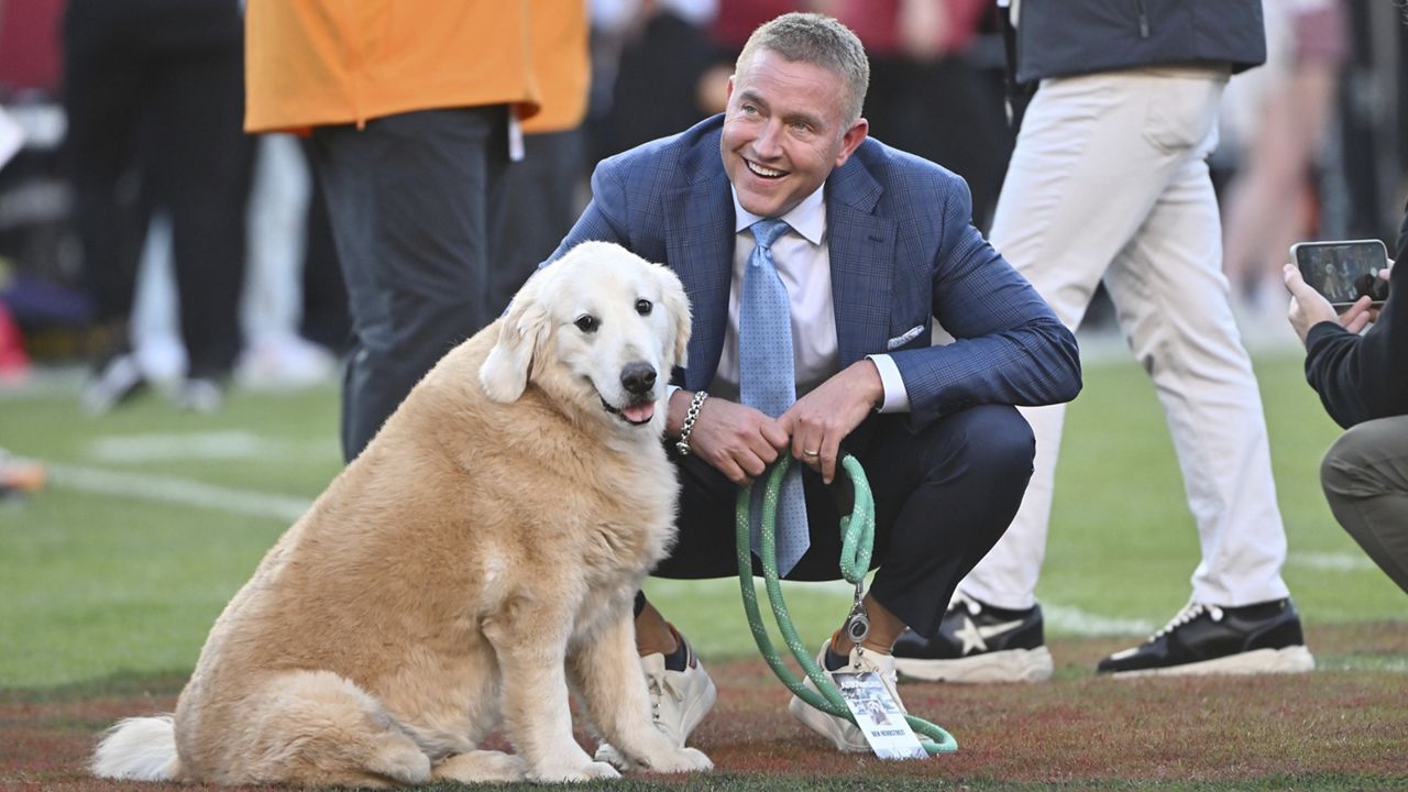 ESPN's Kirk Herbstreit and his dog Ben watch players warm up before the start of an NCAA college football game between Tennessee and Arkansas, Saturday, Oct. 5, 2024, in Fayetteville, Ark. (AP Photo/Michael Woods)