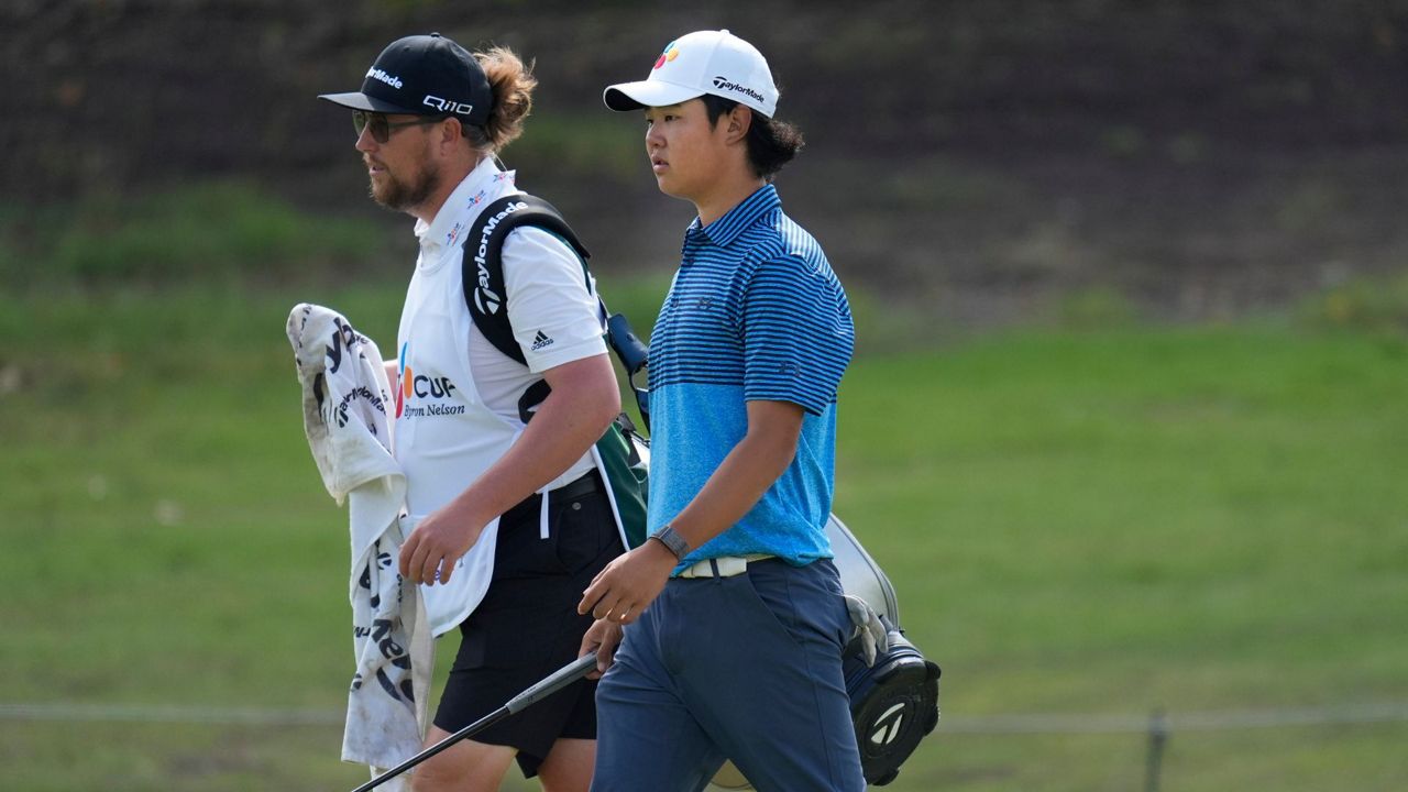 Kris Kim, 16, carries a club as he walks on the 17th green during the first round of the Byron Nelson golf tournament in McKinney, Texas, Thursday, May 2, 2024. (AP Photo/LM Otero)