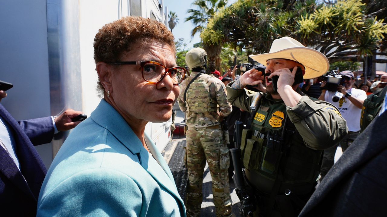 Los Angeles Mayor Karen Bass stands in front of a border patrol federal agent at MacArthur Park Monday, July 7, 2025, in Los Angeles. (AP Photo/Damian Dovarganes)