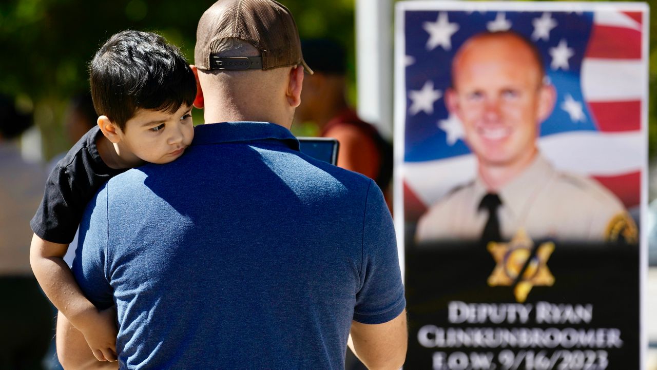 A supporter takes photos of a shrine to Los Angeles County sheriff's deputy Ryan Clinkunbroomer outside of the Palmdale Sheriff's Station Monday, Sept. 18, 2023, in Palmdale, Calif. Deputy Clinkunbroomer was shot and killed while sitting in his patrol car Saturday evening in Palmdale. (AP Photo/Marcio Jose Sanchez)