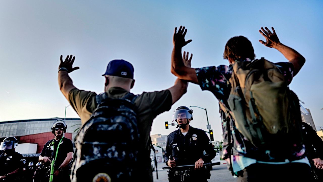 Los Angeles police officers with batons and riot gear attempt to move back protesters in downtown Los Angeles on Monday, June 9, 2025. (AP Photo/Eric Thayer)