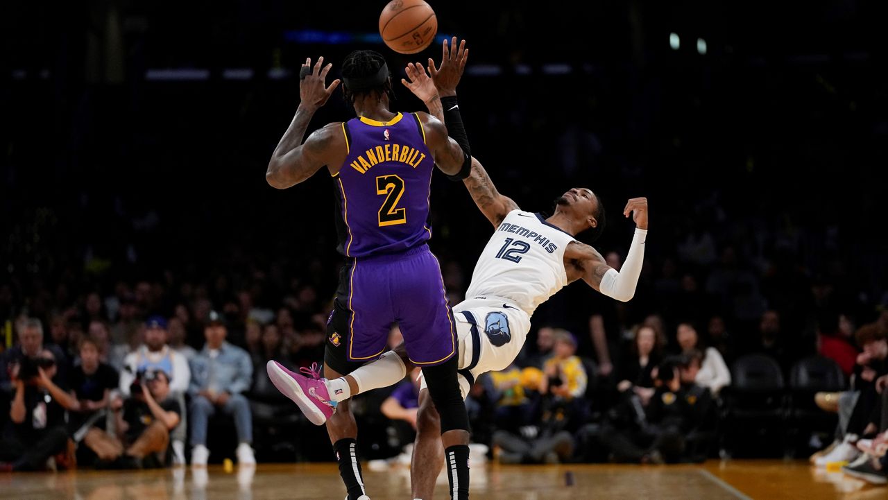 Memphis Grizzlies guard Ja Morant (12) passes the ball against Los Angeles Lakers forward Jarred Vanderbilt (2) during the first half of an NBA basketball game in Los Angeles, Friday, Jan. 5, 2024. (AP Photo/Ashley Landis)