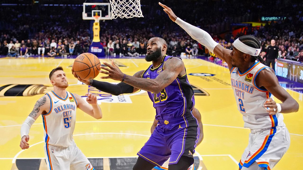 Los Angeles Lakers forward LeBron James, center, shoots as Oklahoma City Thunder center Isaiah Hartenstein, left, and guard Shai Gilgeous-Alexander defend during the first half of an Emirates NBA Cup basketball game, Friday, Nov. 29, 2024, in Los Angeles. (AP Photo/Mark J. Terrill)