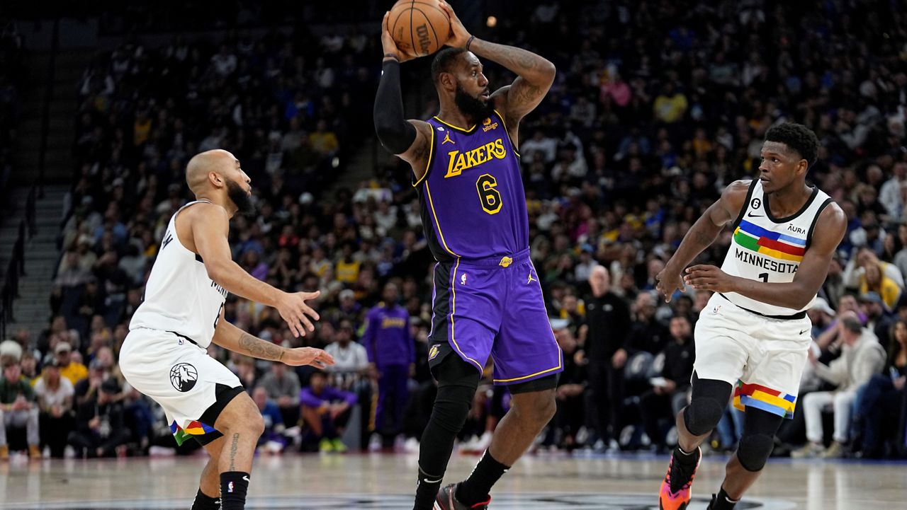 Los Angeles Lakers forward LeBron James (6) handles the ball while defended by Minnesota Timberwolves guard Jordan McLaughlin, left, and guard Anthony Edwards during the second half of an NBA basketball game Friday, March 31, 2023, in Minneapolis. (AP Photo/Abbie Parr)
