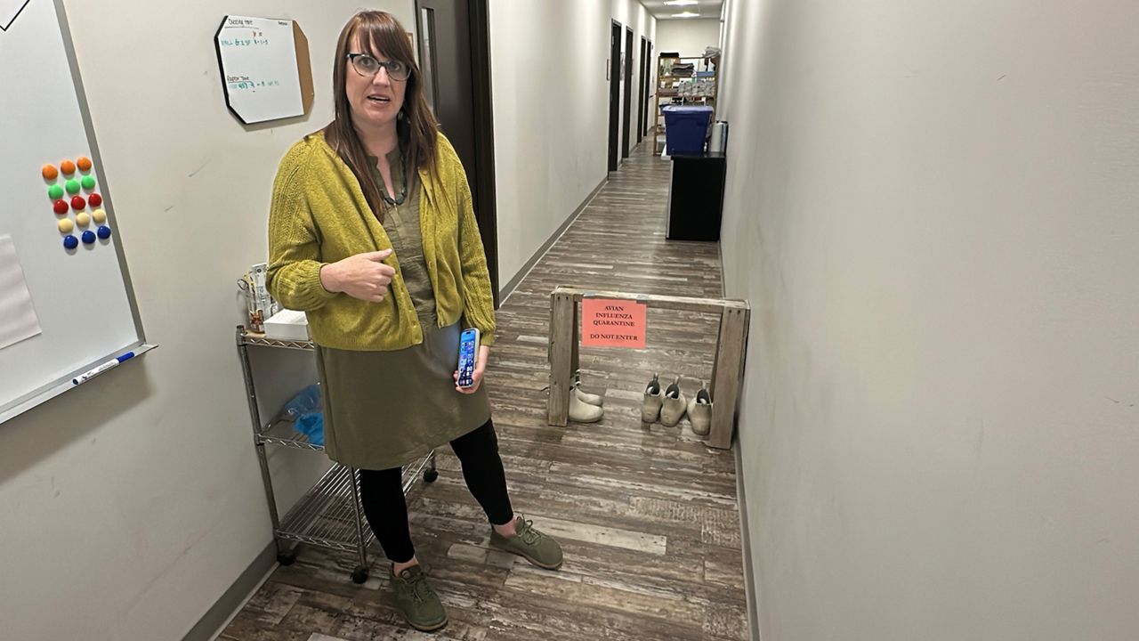 Kristen Lamb, executive director at the Center for Wildlife in York, stands at the barrier to the quarantine area at the center, where clinicians treat birds with avian influenza. Even after more than four years, she says the center is still finding raptors with the disease. (Spectrum News/Sean Murphy)
