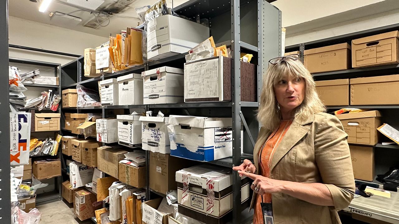 Laura Hudson, director of internal operations for the Maine Office of the State Treasurer, talks about the items being held by the state from abandoned safe deposit boxes earlier this week. (Spectrum News/Susan Cover)