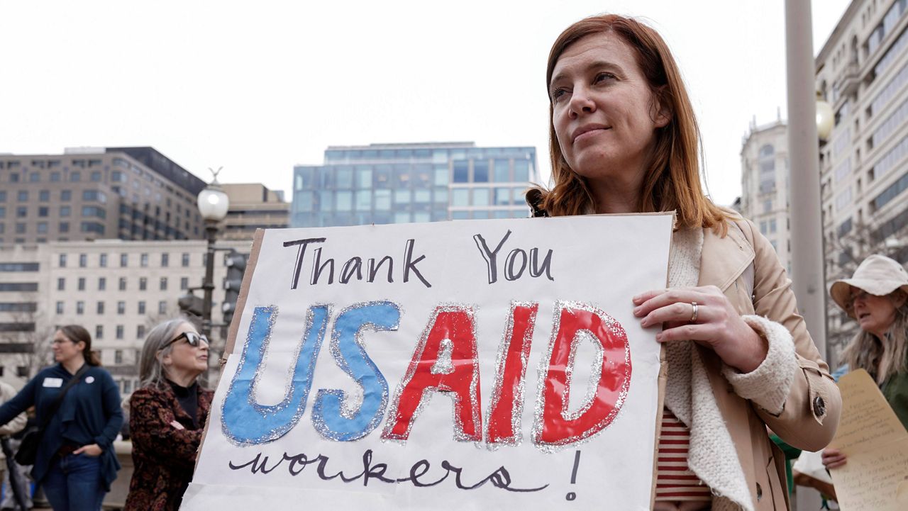 A person carries a sign in support of the United States Agency for International Development workers, as they carry their personal belongings after retrieving them from the USAID's headquarters in Washington, Feb. 27, 2025. (AP Photo/Jose Luis Magana, File)