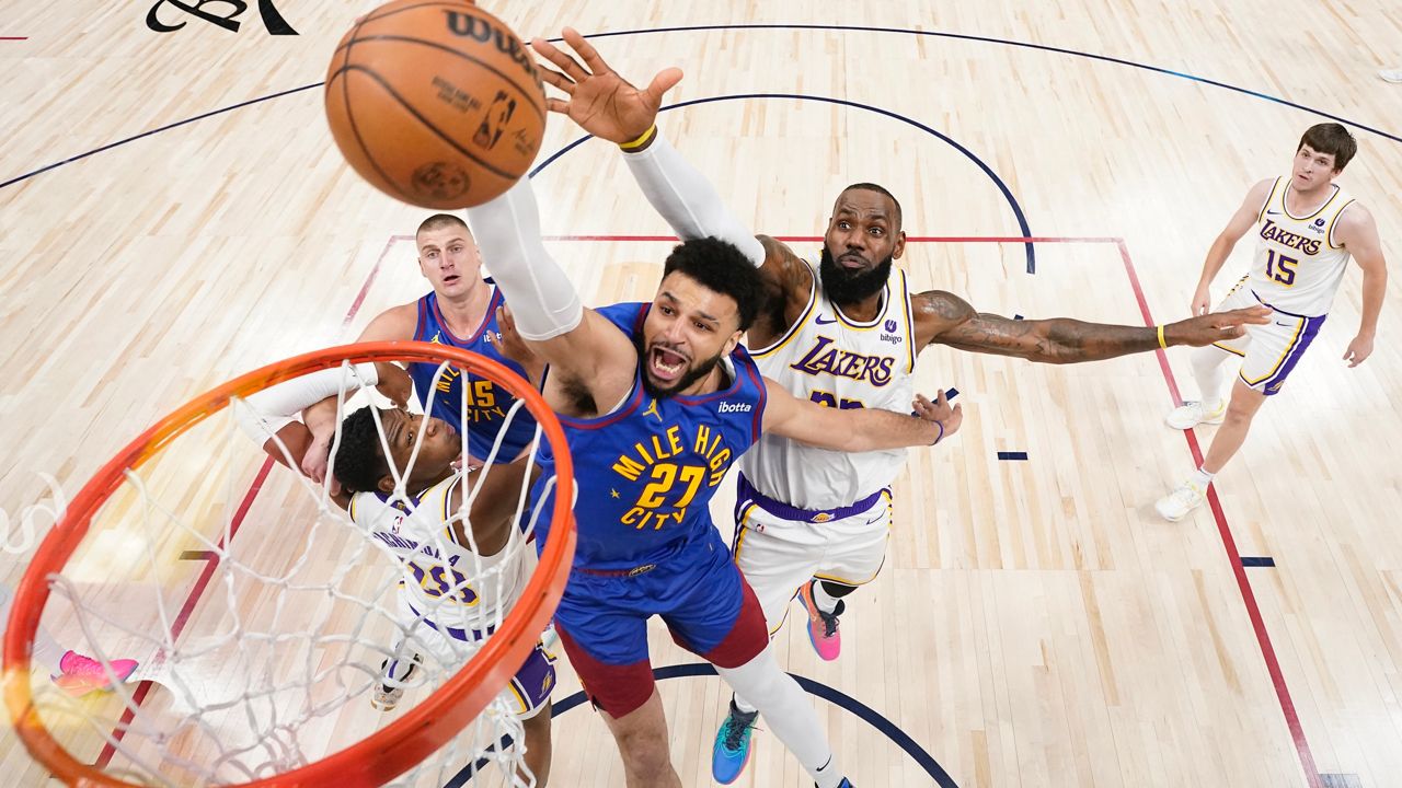Denver Nuggets guard Jamal Murray (27) goes up to shoot against Los Angeles Lakers forward LeBron James, center right, during the first half in Game 1 of an NBA basketball first-round playoff series, Saturday, April 20, 2024, in Denver. (AP Photo/Jack Dempsey)