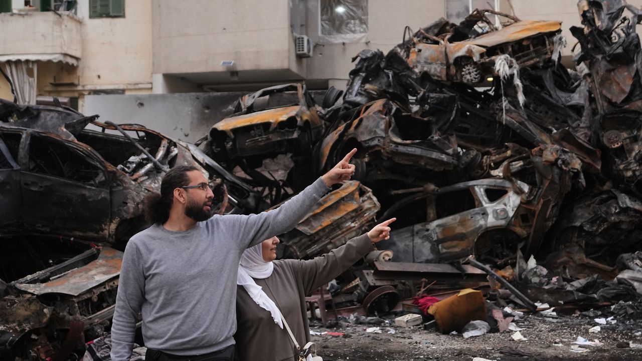 Residents gesture and point toward damage as they stand near charred cars at the site of a building destroyed in an Israeli airstrike last Wednesday in central Beirut, Lebanon, Tuesday, April 14, 2026. (AP Photo/Hassan Ammar)