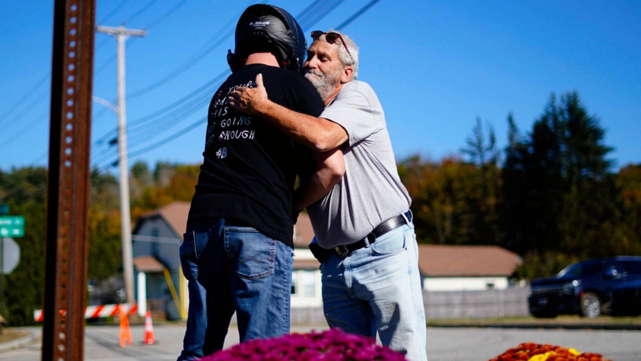 Richard Morlock, right, a member of the deaf community and surviver of the mass shooting at Schemengees Bar and Grille, embraces a person at a makeshift memorial in Lewiston, Maine, Saturday, Oct. 28, 2023. (Associated Press/Matt Rourke)