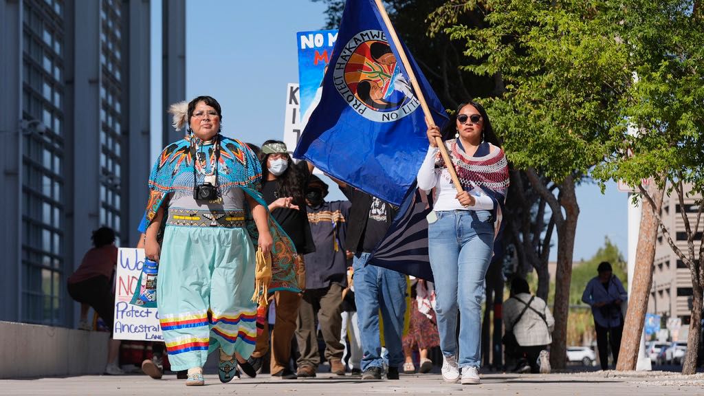 Zoe Perry, left, and Loveena Watahomiegie, right, as they join other members of the Hualapai Tribe while marching in front of U.S. District Court as they gathered to try to persuade a federal judge to extend a temporary ban on exploratory drilling for a lithium project near tribal lands Tuesday, Sept. 17, 2024, in Phoenix. (AP Photo/Ross D. Franklin)