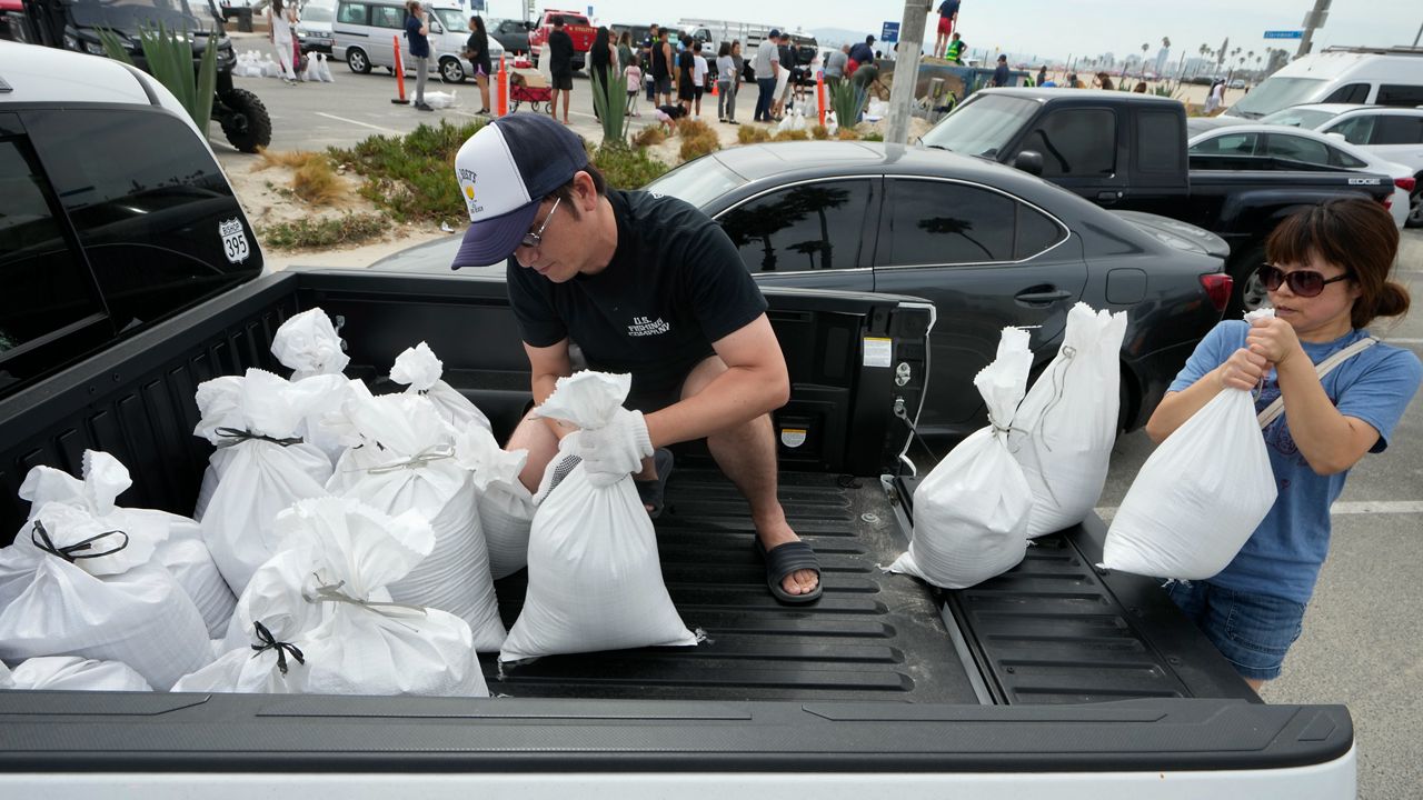 Residents Yuya Jakeguchi and his wife, Nozomi, load sandbags on to the back of their truck ahead of Hurricane Hilary in Long Beach, Calif., Saturday, Aug. 19, 2023. (AP Photo/Damian Dovarganes)