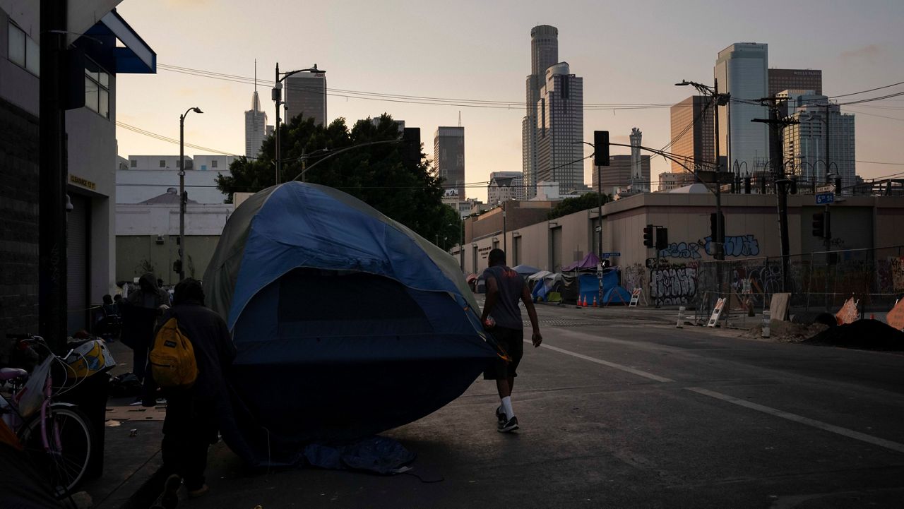 Two homeless men carry a tent in the Skid Row neighborhood of Los Angeles, Thursday, Sept. 14, 2023. (AP Photo/Jae C. Hong)