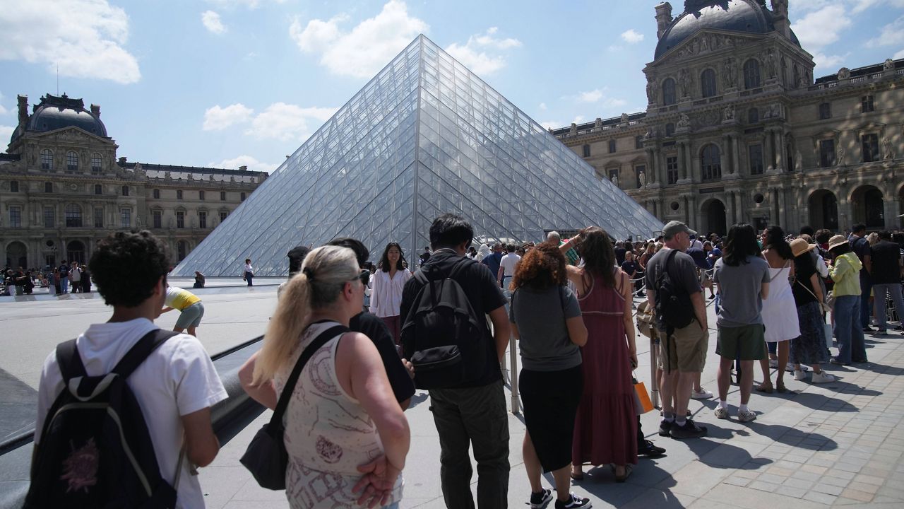 Tourists wait in line outside the Louvre museum which failed to open on time Monday, June 16, 2025 in Paris. (AP Photo/Christophe Ena)