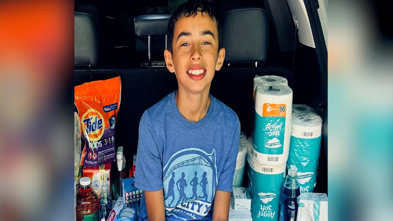 Micah Suttle, 11, sits in front of donated supplies he helped collect with his fifth-grade class to support families transitioning out of homelessness (courtesy of Home for Families).