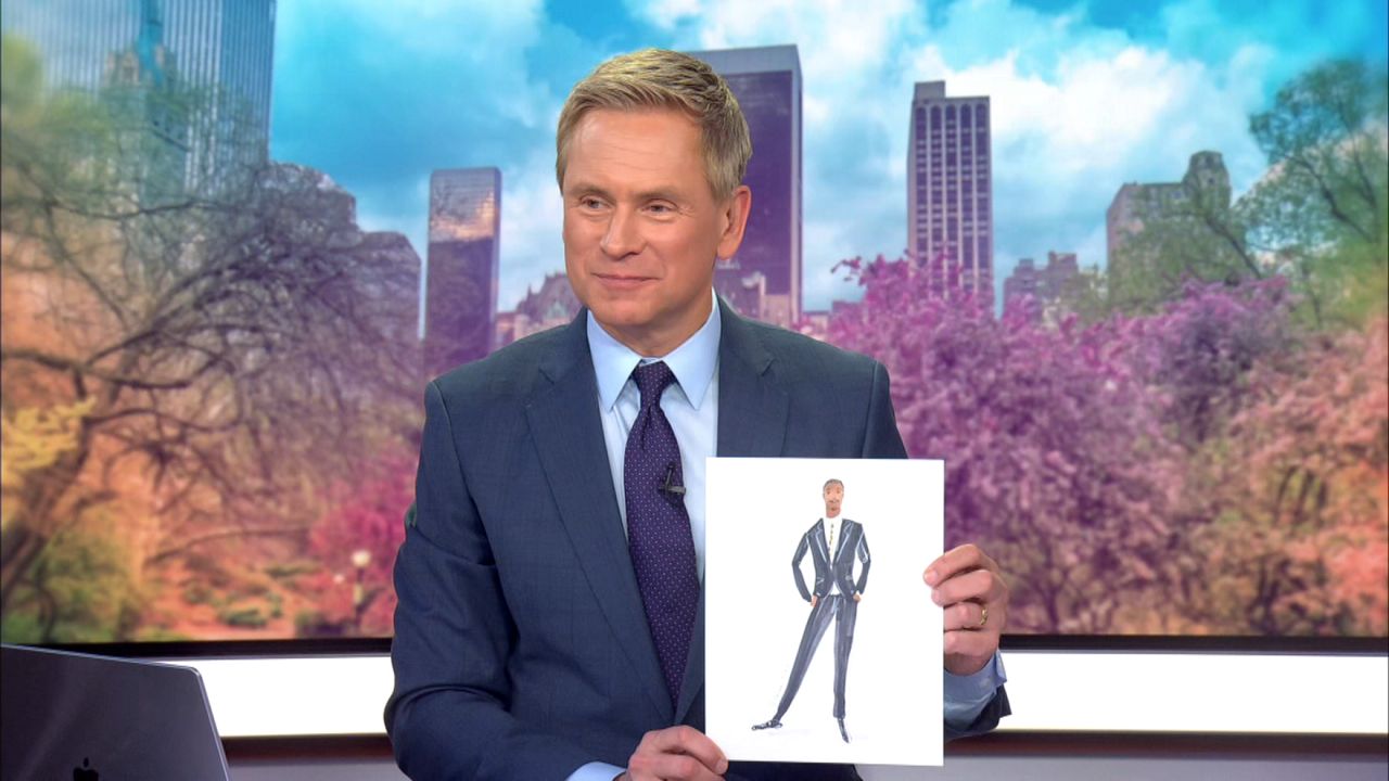Pat Kiernan holds a sketch of Guy Brown done by fashion illustrator Deanna First on “Mornings On 1” Wednesday. (Spectrum News NY1)