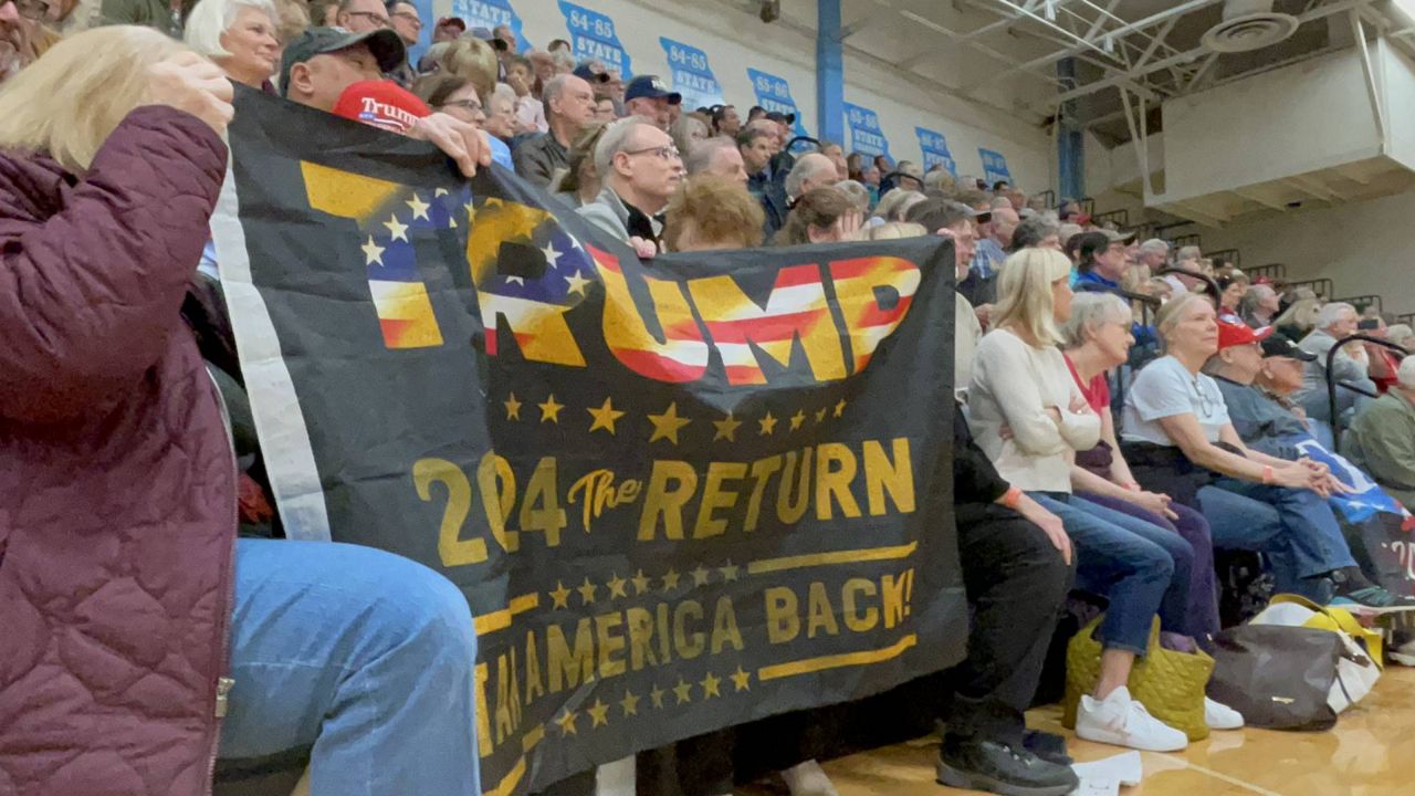 Supporters of former President Donald Trump hold up a sign during Saturday's caucus at Parkway West High School in Chesterfield, Mo. Trump won the St. Louis County site handily and also carried the rest of the state. (Spectrum News/Gregg Palermo)