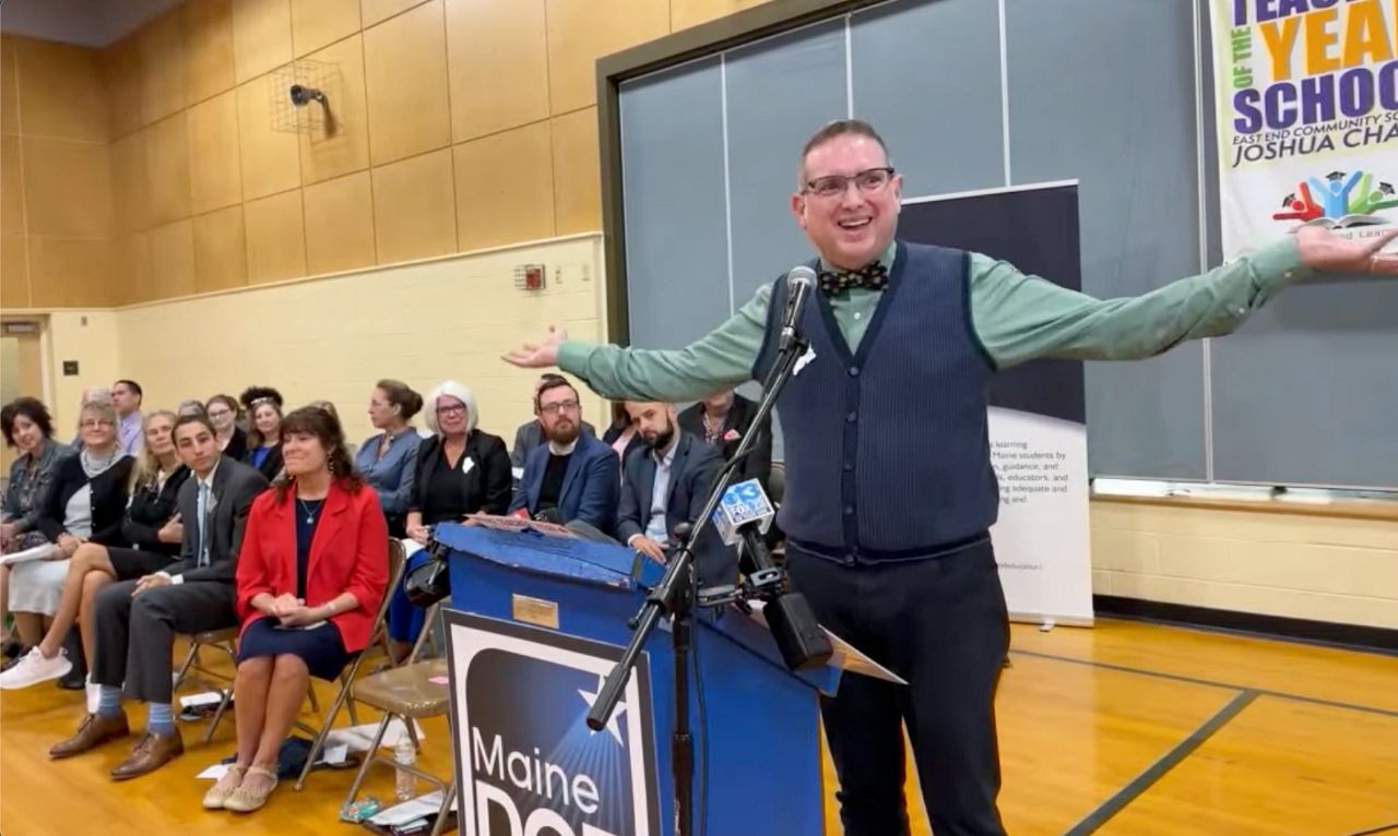 Joshua Chard, a third grade teacher at East End Community School in Portland, addresses a surprise assembly gathered to honor him as Maine’s 2024 Teacher of the Year. (Still image via YouTube)