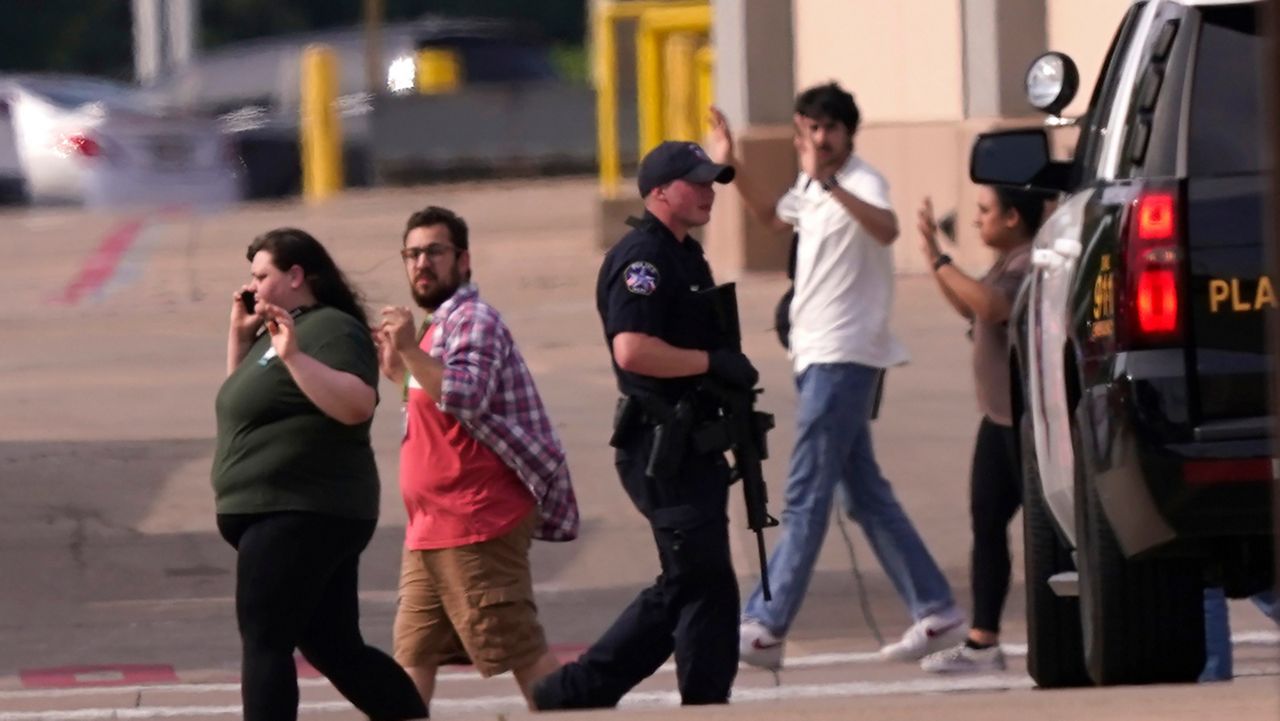 People raise their hands as they leave a shopping center following reports of a shooting, Saturday, May 6, 2023, in Allen, Texas. (AP Photo/LM Otero)