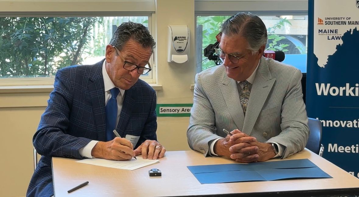 University of Maine System Chancellor Dannel Malloy, left, signs an agreement to guarantee admission to community college graduates Wednesday alongside Maine Community College System President David Daigler. (Spectrum News/Susan Cover)