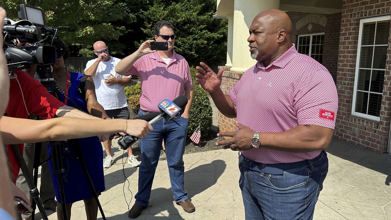 North Carolina Republican gubernatorial candidate Mark Robinson, right, speaks with reporters outside the Olympic Family Restaurant in Colfax, N.C., where Robinson held a campaign event on Monday, Aug. 26, 2024. (AP Photo/Gary D. Robertson)