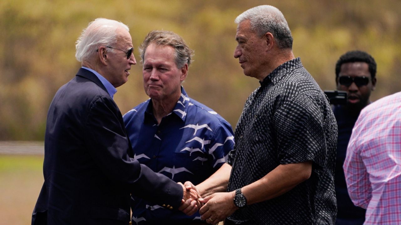 President Joe Biden greets Maui Country Mayor Richard Bissen at Kapalua Airport as he visits areas devastated by the Maui wildfires, Monday, Aug. 21, 2023, in Lahaina, Hawaii. In the center is Rep. Ed Case, D-Hawaii. (AP Photo/Evan Vucci)