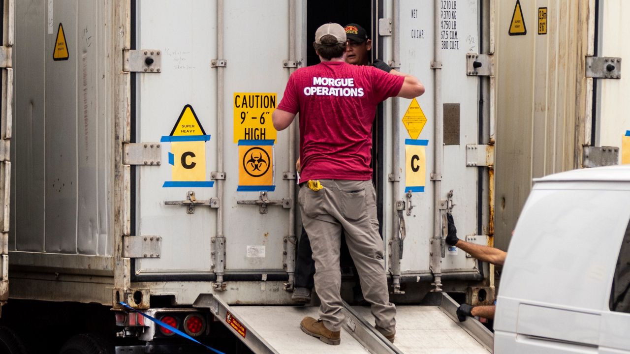 Technicians are seen outside a refrigerated truck used as a mobile morgue for wildfire victims at the Maui Police Forensic Facility in Wailuku on the island of Maui, Hawaii Tuesday, Aug. 15, 2023. (Stephen Lam/San Francisco Chronicle via AP)