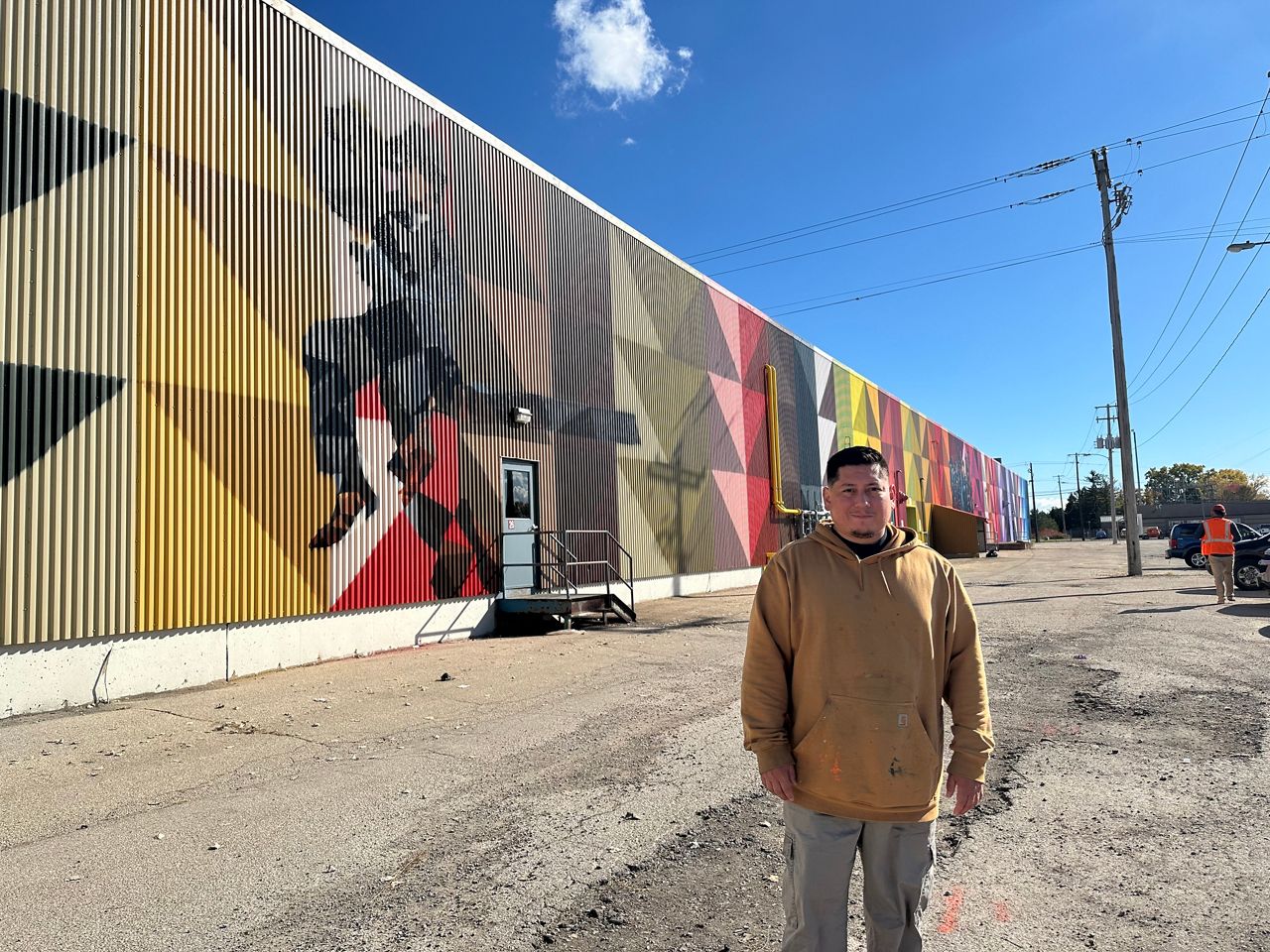 Photo of Mauricio Martinez with his mural in Oshkosh.