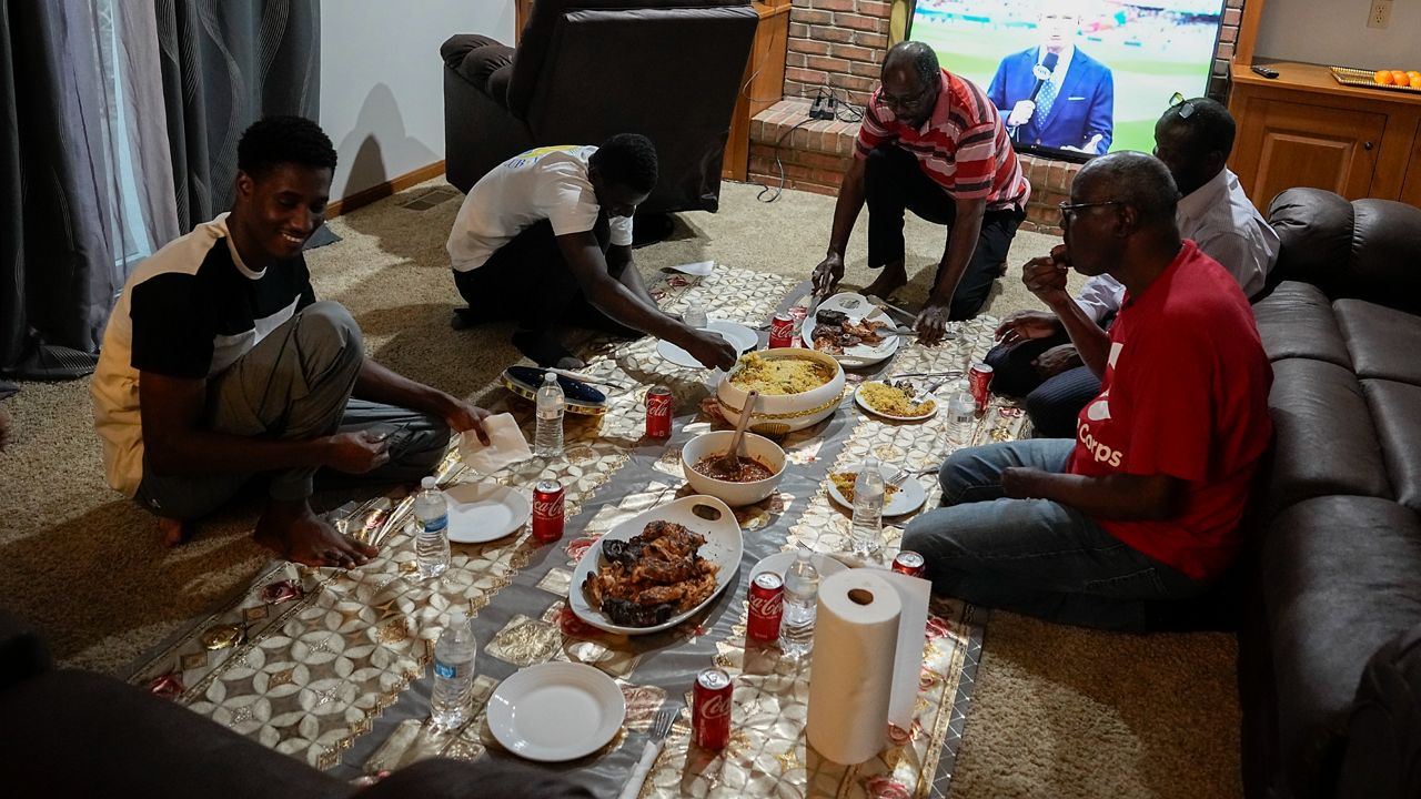 Mauritanians gather for a traditional meal, Friday, July 21, 2023, in Cincinnati. A new surge in migration from Mauritania to the U.S. was made possible by the discovery this year of a new route through Nicaragua, where relaxed entry requirements allow Mauritanians and a handful of other foreign nationals to purchase a low-cost visa without proof of onward travel. (AP Photo/Darron Cummings)