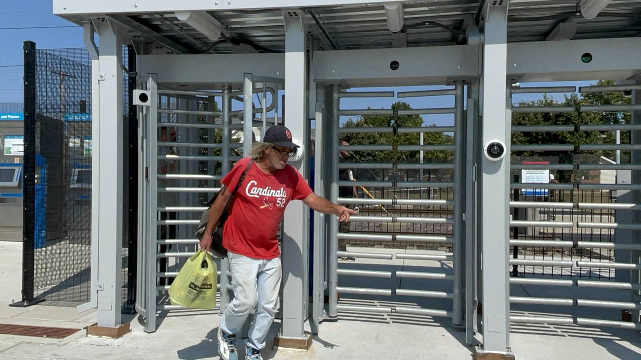 A MetroLink customers passes through new security gates in place at the mass transit system's Emerson Park stop in East St. Louis, Ill. on Monday, the first day the system is in use. Three more Metro East locations will start using the gates in September, with a rollout at some Missouri stops coming by the end of the year. (Spectrum News/Gregg Palermo)