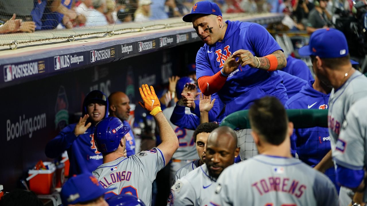 New York Mets' Pete Alonso, lower left, high fives a teammate after hitting an RBI sacrifice fly during the eighth inning of Game 1 of a baseball NL Division Series against the Philadelphia Phillies on Saturday, Oct. 5, 2024, in Philadelphia. (AP Photo/Chris Szagola)