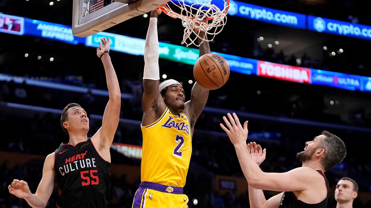 Los Angeles Lakers forward Jarred Vanderbilt, center, dunks as Miami Heat forward Duncan Robinson, left, and forward Kevin Love defend during the first half of an NBA basketball game Wednesday, Jan. 3, 2024, in Los Angeles. (AP Photo/Mark J. Terrill)